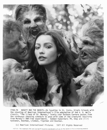 Five creature with hair covering their faces and heads are crowded around Barbara Carrera in a scene...
