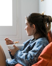 woman eating in bed, what to eat after a miscarriage to help your body heal