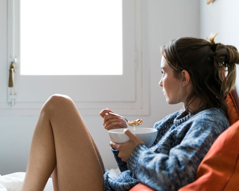 woman eating in bed, what to eat after a miscarriage to help your body heal