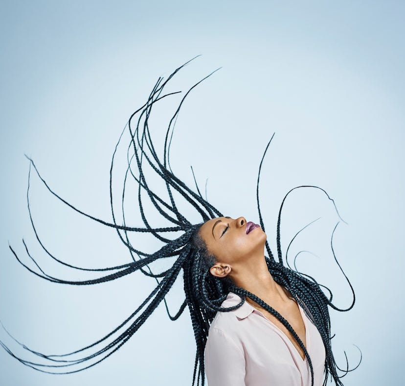 young woman flicks her braids backwards as she thinks about her july 18, 2022 weekly horoscope