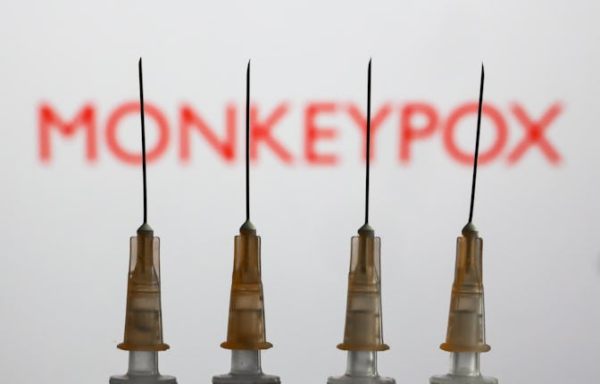 Medical syringes are seen with 'Monkeypox' sign displayed on a screen in the backgound in this illus...