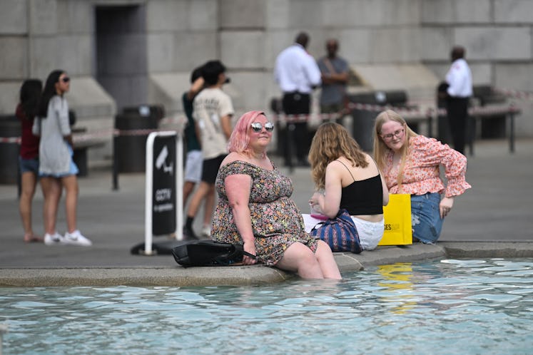 Pedestrians cool off with their feet in the water of the Trafalgar Square fountain, in central Londo...