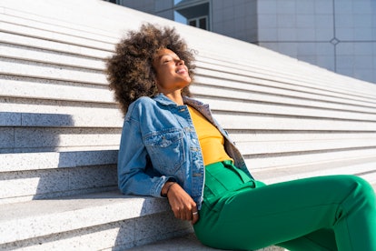 young woman relaxes on steps as she thinks about her july 25, 2022 horoscope