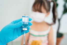 Girl to be vaccinated against COVID-19 with coronavirus vaccine drawn into an injection needle by he...