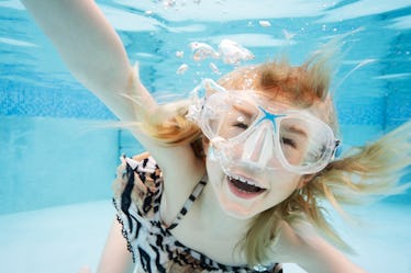 Young girl 7 yrs old, in swimming pool, swimming towards camera