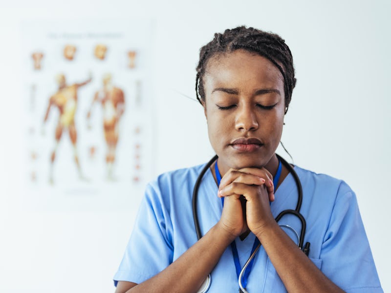 Young female nurse with folded arms standing in hospital