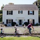 Father and twin 4-year-old sons riding bicycles in front of suburban home