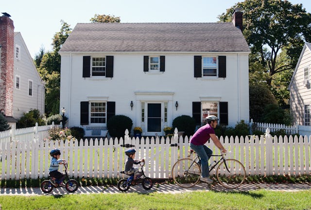 Father and twin 4-year-old sons riding bicycles in front of suburban home