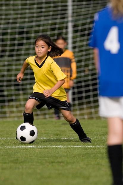 young girl playing soccer in yellow uniform, extracurricular activities for kids