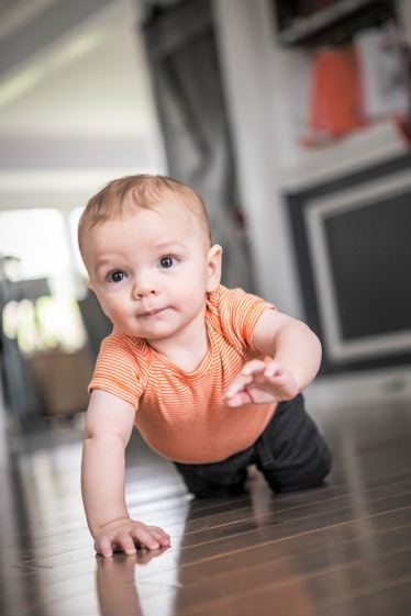 一个8个月大的男婴在他家的硬木地板上爬行。