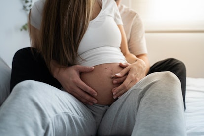 A pregnant woman with her partner in an article about safe sex positions during pregnancy and if mis...