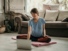 Beautiful young woman doing workouts at home. Young woman sitting in front of her laptop and watchin...