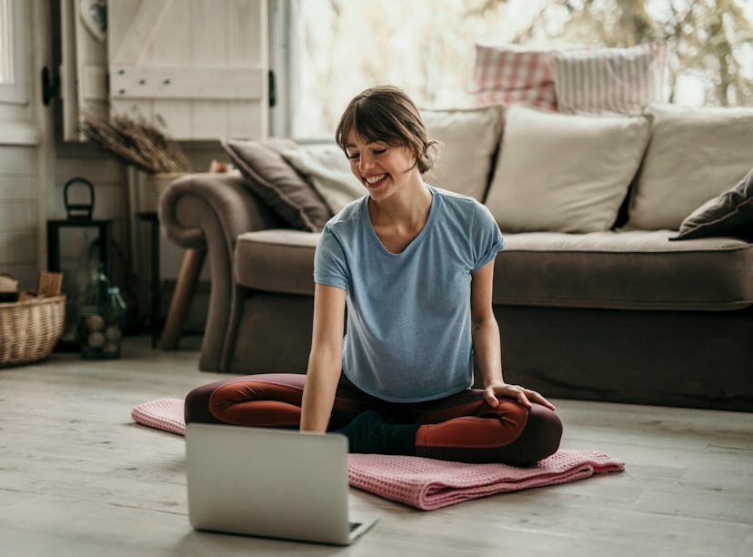 Beautiful young woman doing workouts at home. Young woman sitting in front of her laptop and watchin...