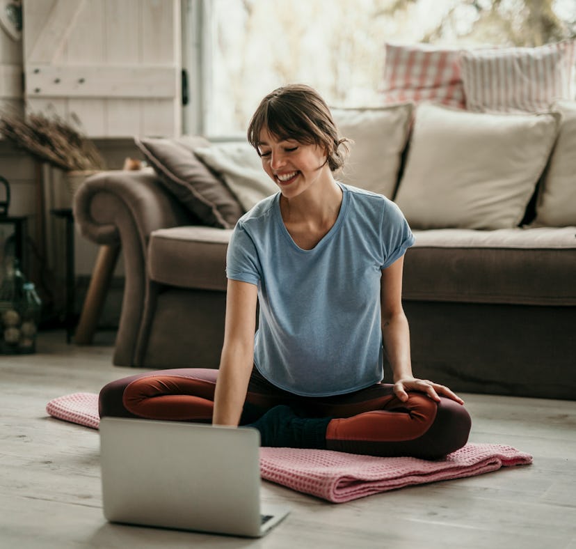Beautiful young woman doing workouts at home. Young woman sitting in front of her laptop and watchin...