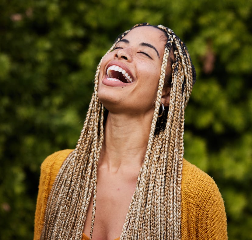 young woman tosses her head back and laughs as she thinks about how the july 2022 new moon in Leo wi...