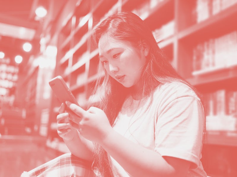 Young women use mobile phones to check in the library