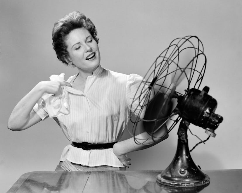 1950s WOMAN COOLING WITH SWIVEL FAN (Photo by Debrocke/ClassicStock/Getty Images)