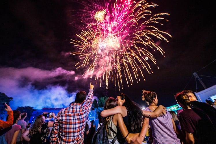 Rear view of crowd of people watching fireworks at night.