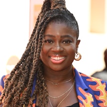 Clara Amfo wearing a purple, orange and yellow patterned suit jacket. Her hair is in braids and a po...