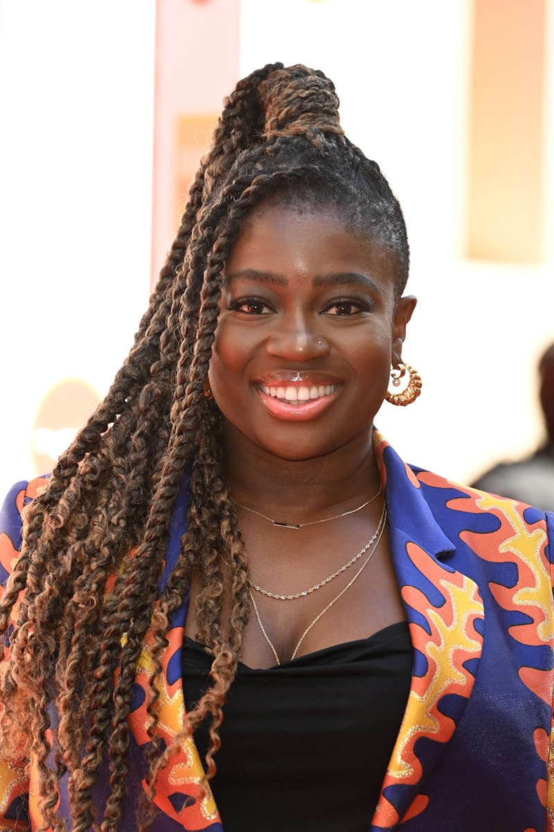 Clara Amfo wearing a purple, orange and yellow patterned suit jacket. Her hair is in braids and a po...