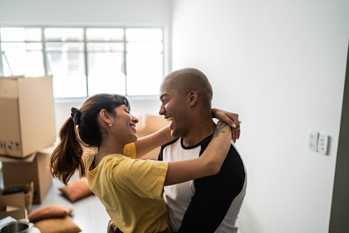 Happy young couple embracing and dancing when moving house. How to manifest someone, according to ex...