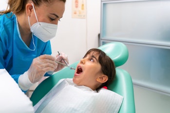 Dentist at the dentist's office examining the girl's teeth