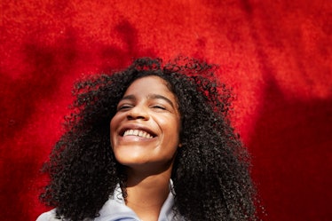 Young woman smiles as she reflects on the spiritual meaning of the July 2022 new moon in Leo.