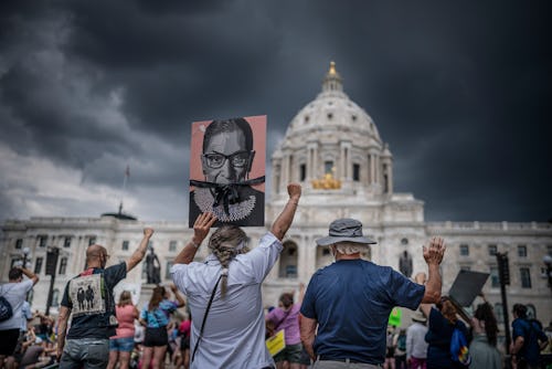 ST. PAUL, MN. - JULY 2022: Micah Kender, left carrying a poster of former Supreme Court Justice Ruth...