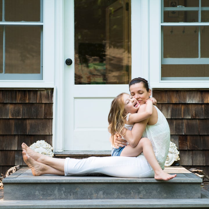Mother sitting in front of a house hugging her daughter