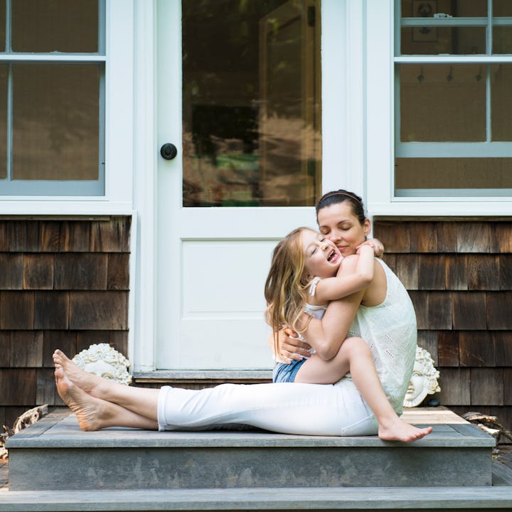 Mother sitting in front of a house hugging her daughter