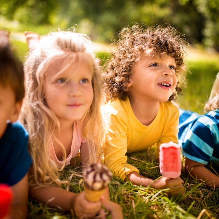 Sweet mixed racial group of happy friendly children eating ice creams in a park together