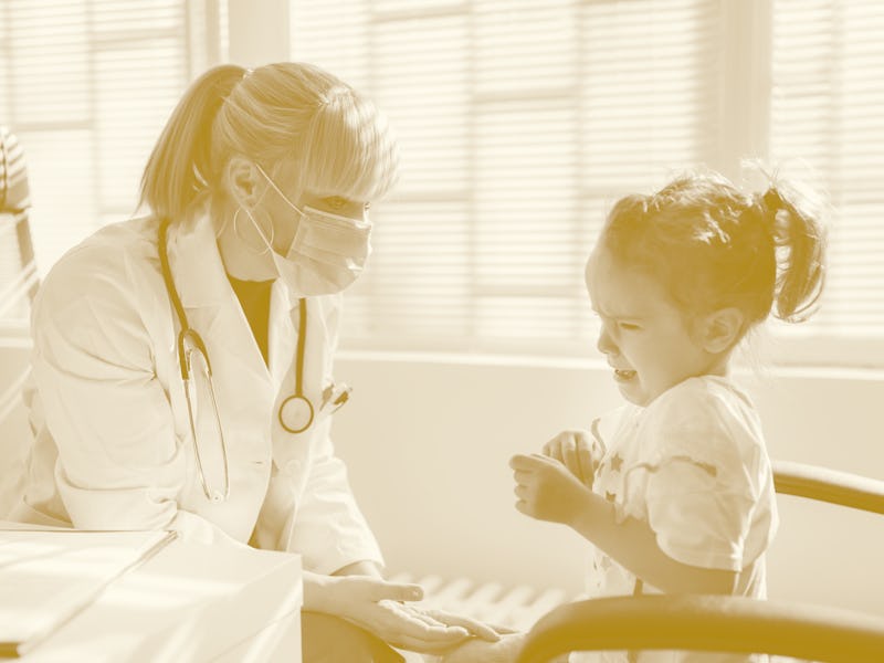 Sad young girl crying at doctor's office while the doctor is trying to console her before the exam