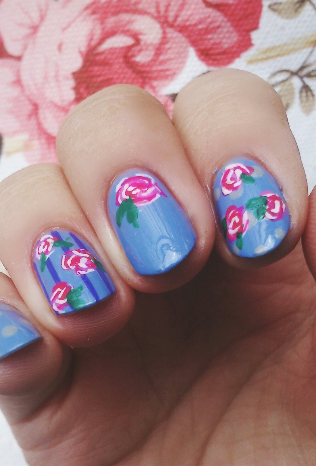 Purple manicured nails with light and dark pink floral nail designs.