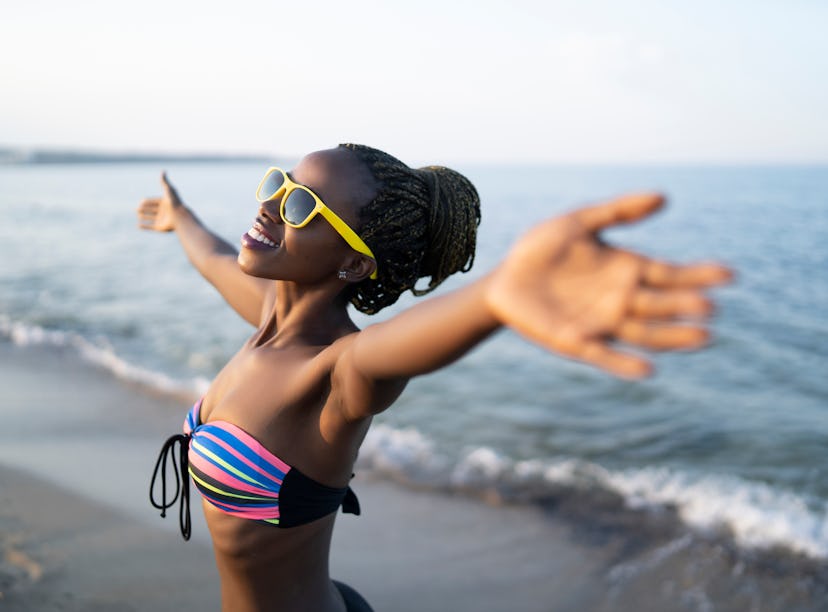 African woman having fun at beach, hands outstratched