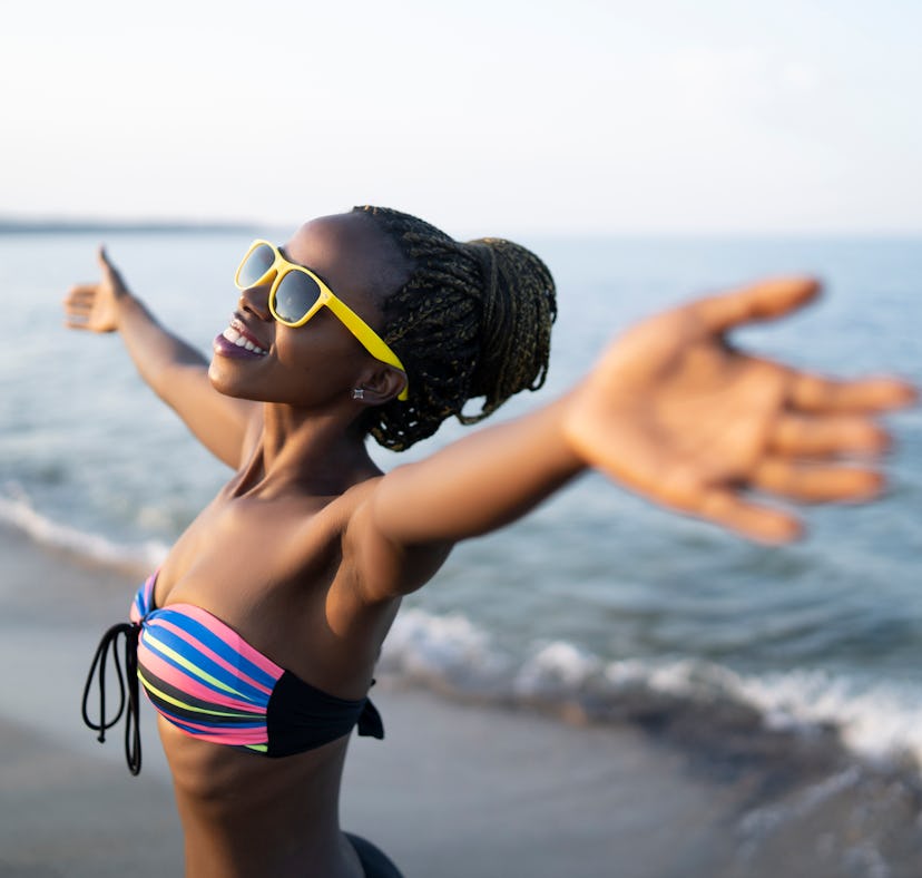 African woman having fun at beach, hands outstratched