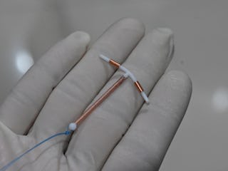 This picture taken on June 25, 2020 shows a doctor holding an IUD birth control device to put into a...