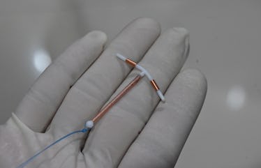 This picture taken on June 25, 2020 shows a doctor holding an IUD birth control device to put into a...