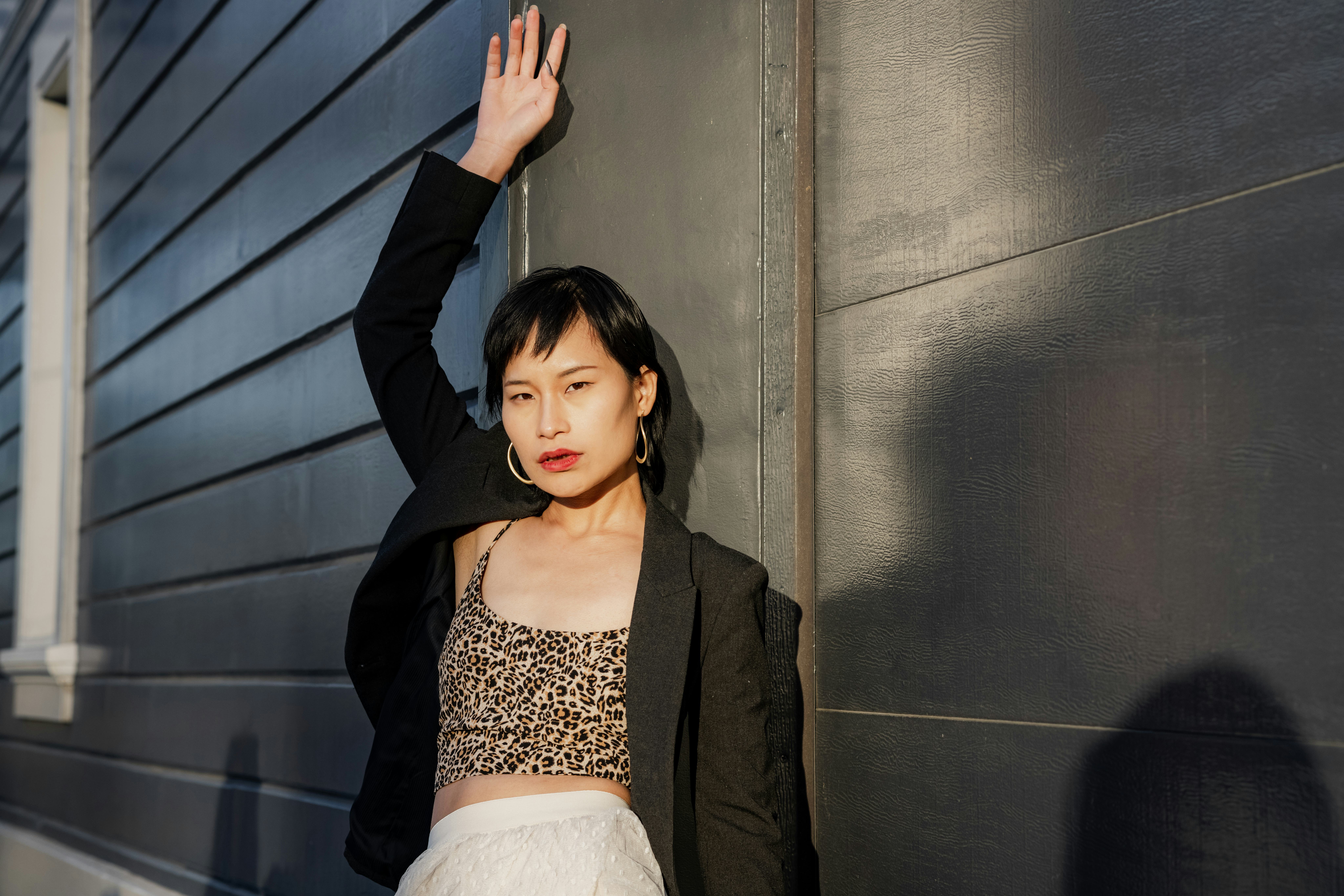 Portrait of a confident young woman standing against black background . She is posing to camera. The...