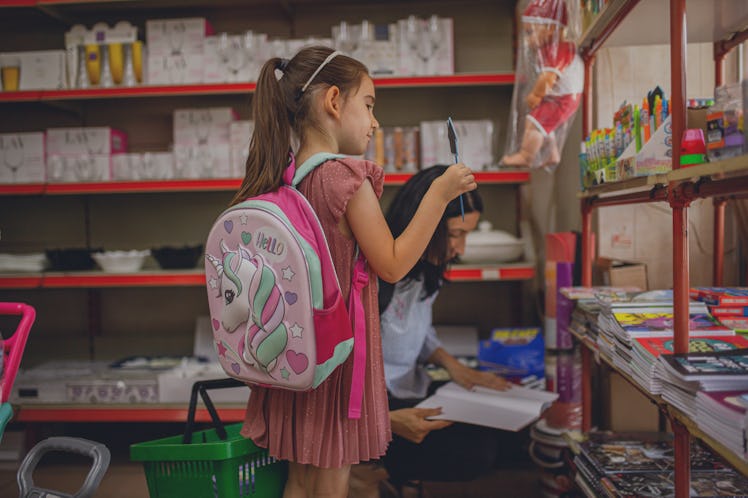 A little kid goes back to school shopping with a backpack on