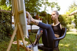 A woman paints a canvas with her feet. Here's how the July 2022 new moon will affect each zodiac sig...