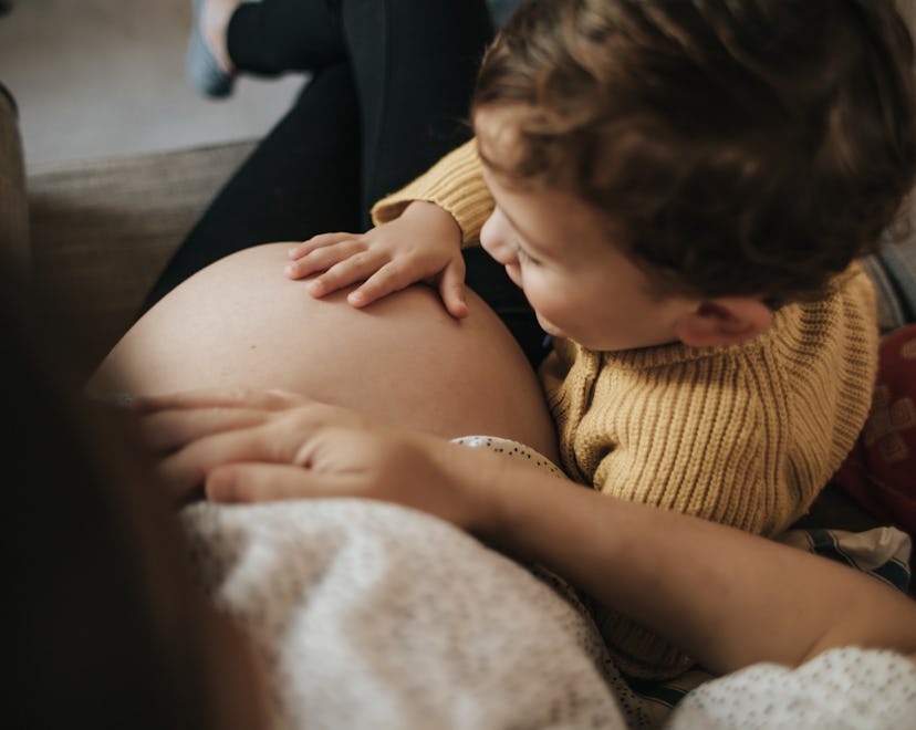 Boy touching his pregnant mother's belly in an article about how to tell your in-laws that you're pr...