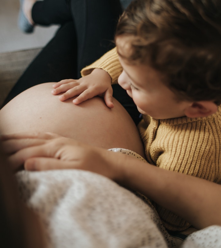 Boy touching his pregnant mother's belly in an article about how to tell your in-laws that you're pr...