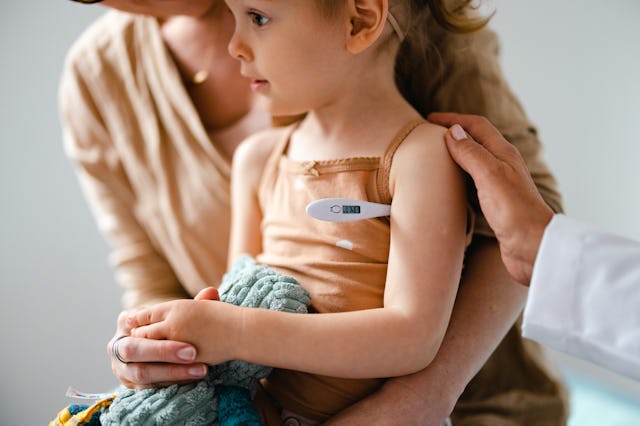 Cropped shot of an anonymous girl holding a toy while waiting for her temperature to be measured wi...