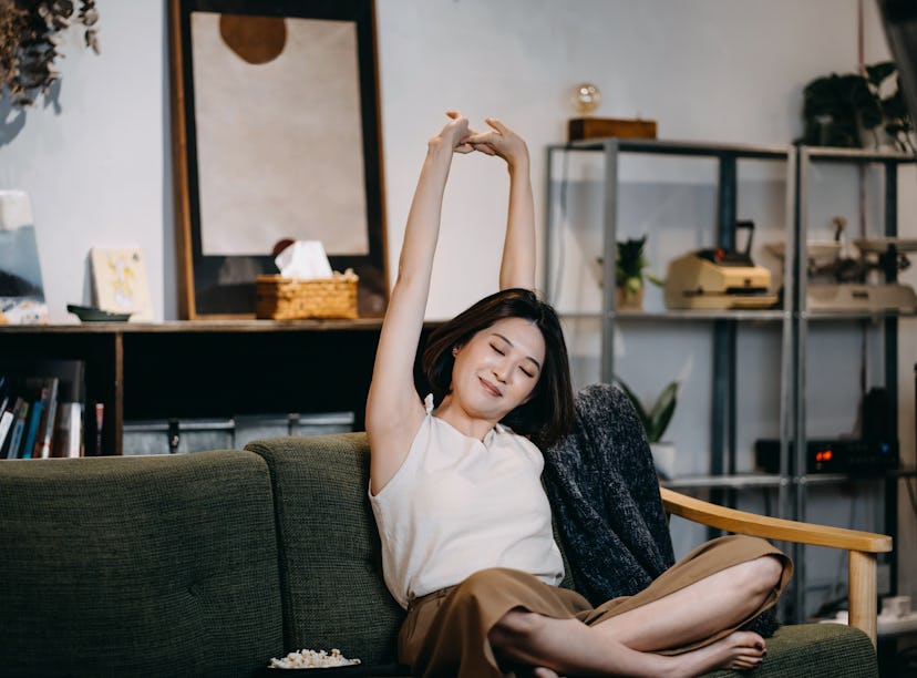 Young woman with her eyes closed stretching arms as one of the zodiac signs who will have the worst ...