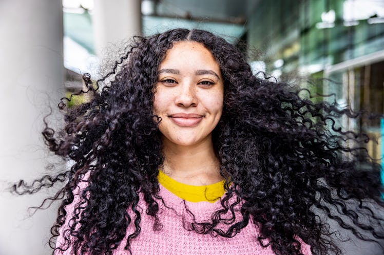 young woman smiles as she thinks about her August 1, 2022 weekly horoscope.