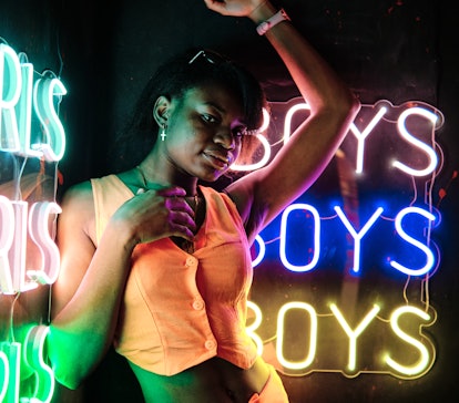 Young woman looking at the camera while posing near colorful neon signs on the most romantic day in ...