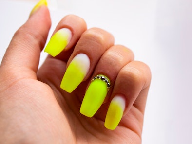 A closeup of bright yellow neon summer nails.
