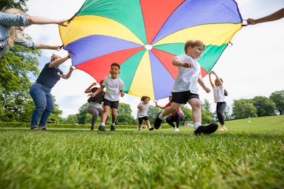 Children playing with a parachute at school in an article about what if your kid misses you at schoo...