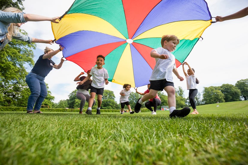 Children playing with a parachute at school in an article about what if your kid misses you at schoo...