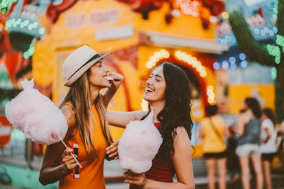 two friends enjoy a festival as they enjoy cotton candy and discuss leo compatibility 